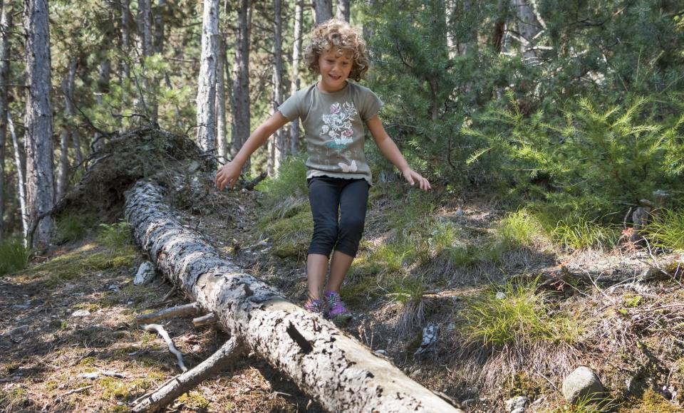 Ein Kind balanciert auf einem Baumstamm
